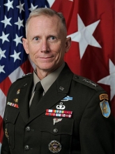 headshot of DA Sims, a man with a flag in the background and a decorated military jacket