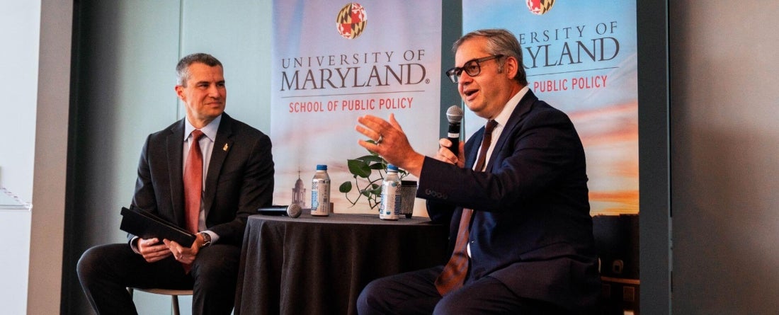 Dean Gustavo Flores-Macias sits with Azerbaijan Ambassador Ibrahim with 2 UMD banners behind them